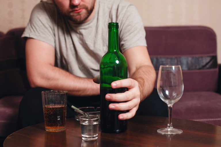 Anonymous alcoholic person hard drinking alone.