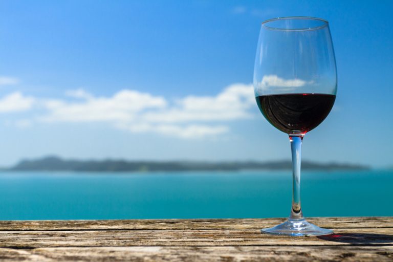 A Glass of Red Wine Standing on Old Table at the Beach on the Pacific Coast, Auckland, New Zealand